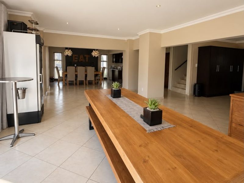 Spacious open-plan living and dining area featuring neutral tiled flooring, recessed lighting, and a functional layout connecting to the kitchen and staircase.