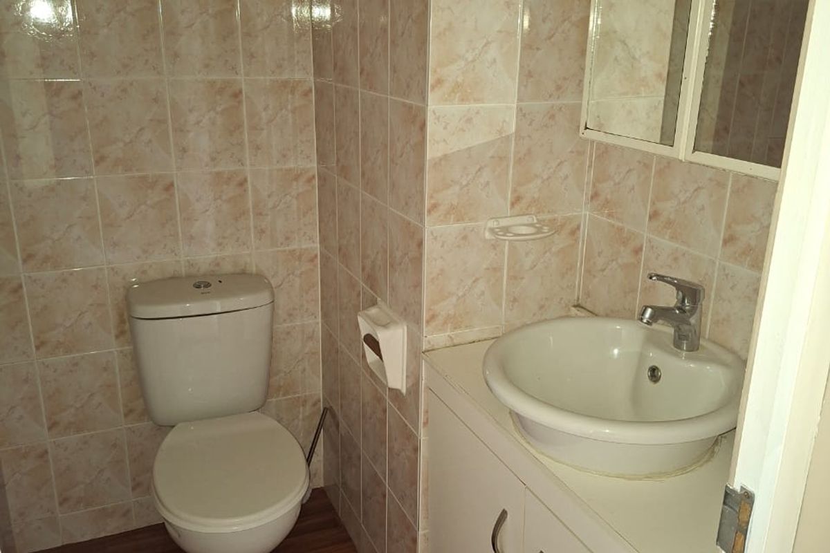 A compact bathroom featuring a vanity cabinet with basin, toilet, and full-height wall tiling.