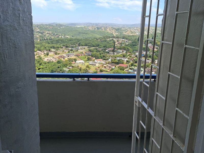 A balcony featuring a metal security gate and a railing, offering an expansive elevated view of the surrounding residential landscape.