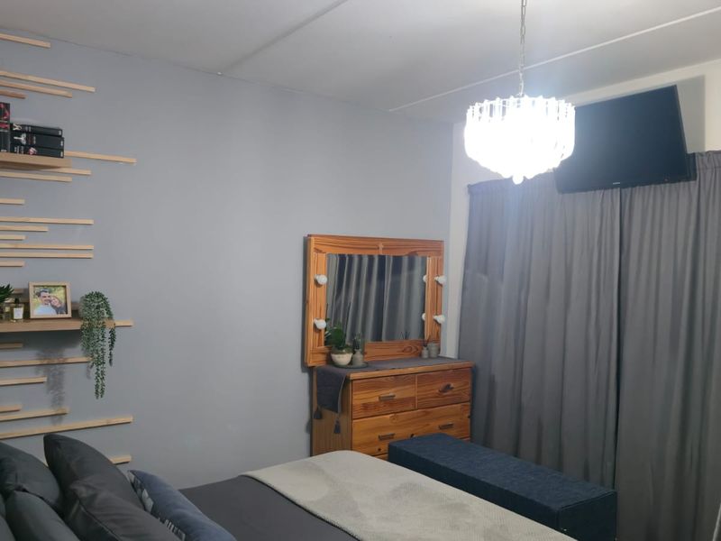 A well-maintained bedroom featuring decorative wall slats and a central ceiling light fixture, providing a comfortable and modern living space.