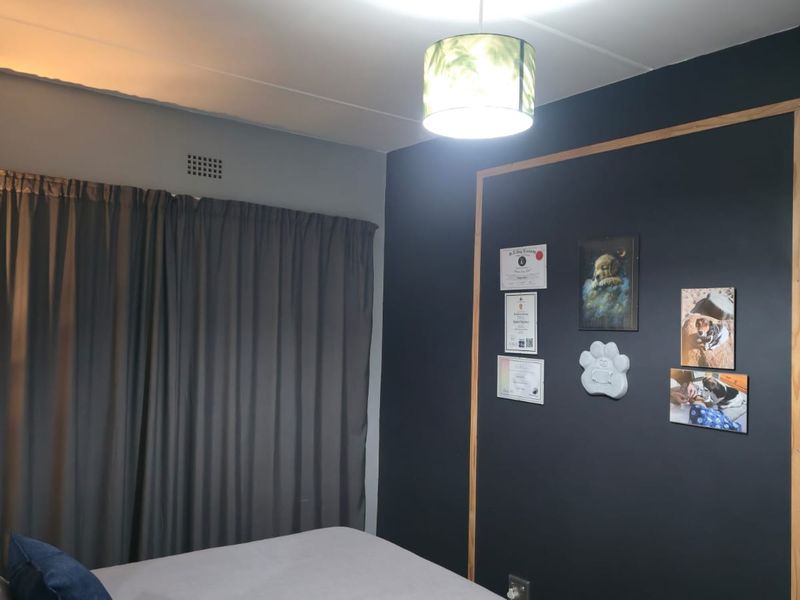 A bedroom featuring a dark accent wall with timber trim detailing and a ceiling-mounted light fixture.