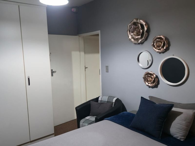 A bedroom featuring a built-in wardrobe and neutral grey wall finishes, providing a functional and comfortable sleeping space.