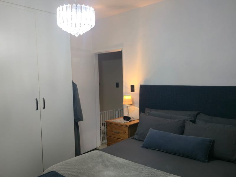 A well-maintained bedroom featuring a large built-in wardrobe and modern ceiling lighting, providing a clean and functional living space.