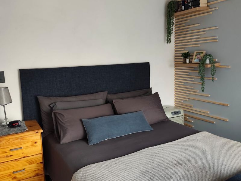 A well-maintained bedroom featuring a decorative wood-slat accent wall, built-in shelving, and a modern crystal chandelier.