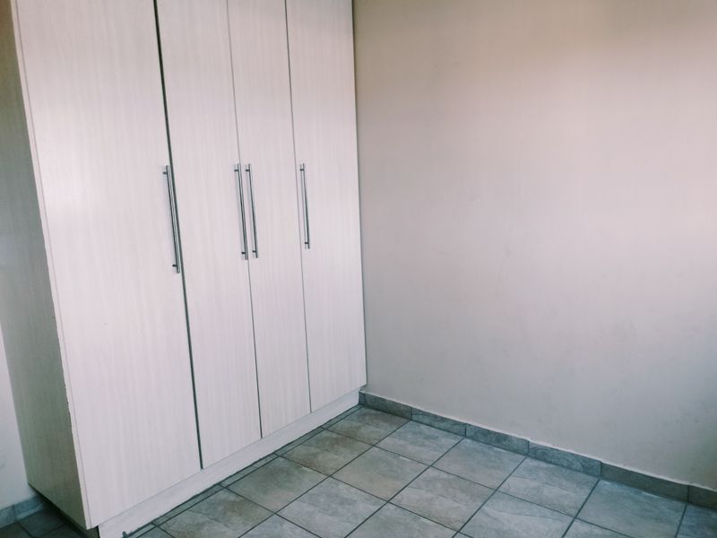 A clean, empty bedroom featuring neutral tiled flooring and modern built-in cupboards, providing a blank canvas for personalization.