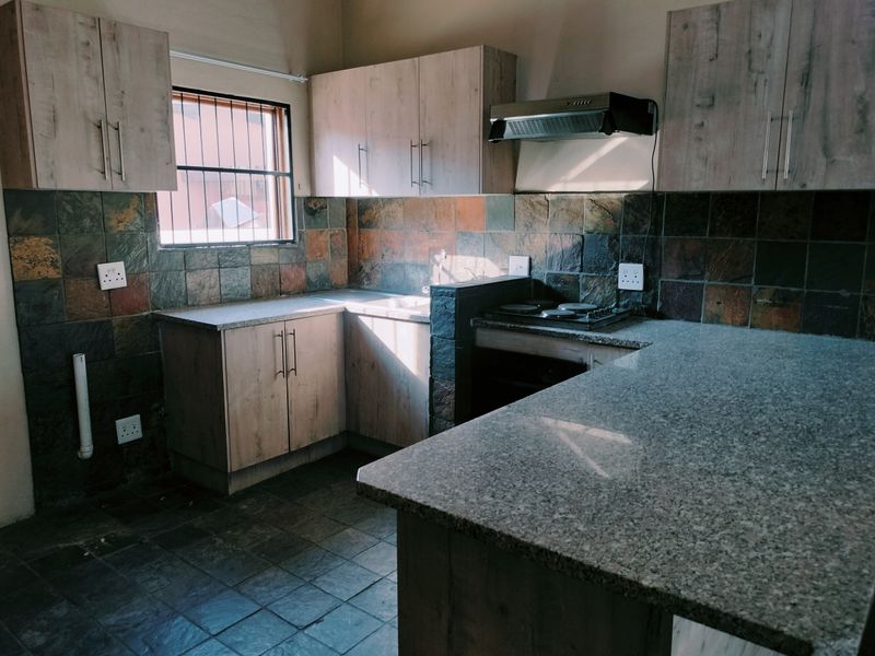A functional kitchen featuring built-in cabinetry, granite countertops, and slate tile finishes, offering a practical layout for daily use.
