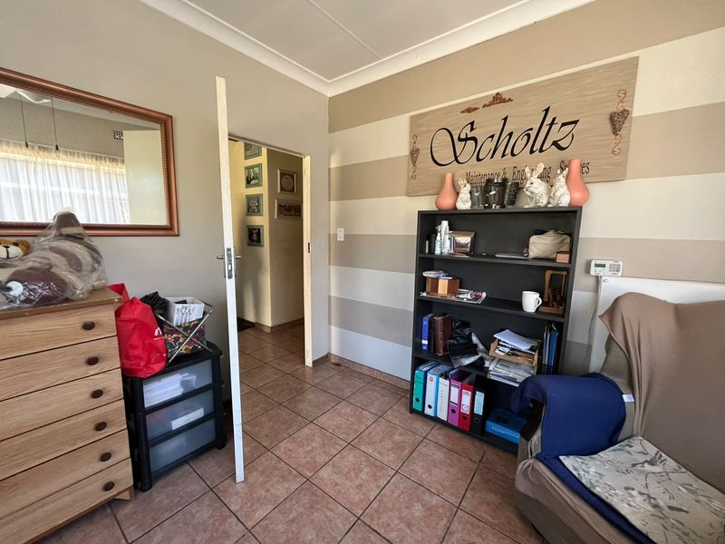 A living area featuring tiled flooring and coved ceilings, currently utilized as a home office space.