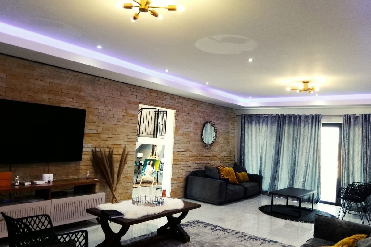 Spacious living room featuring a textured stone accent wall, recessed ceiling lighting, and large sliding glass doors leading to the exterior.