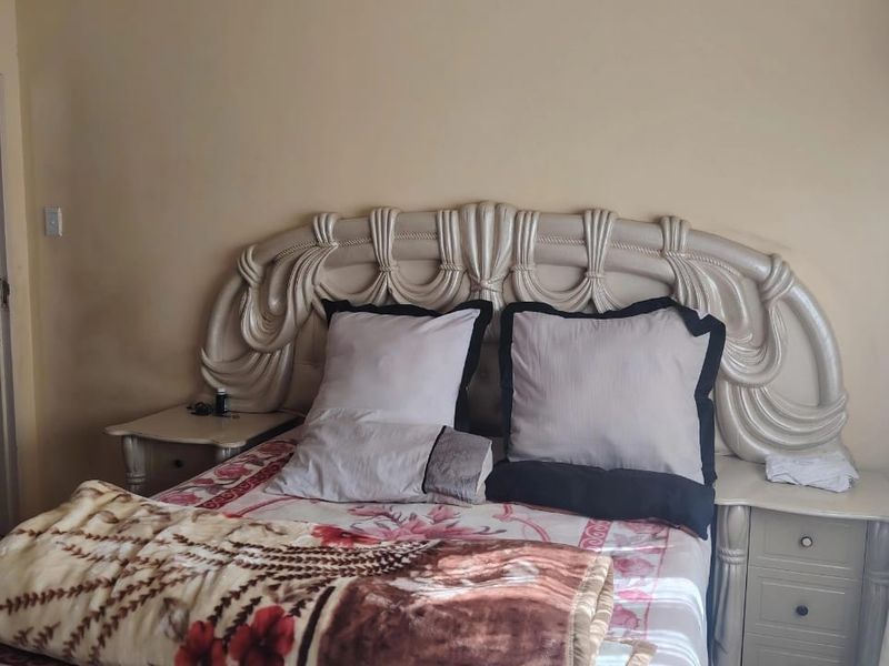 A bedroom featuring a decorative headboard and integrated bedside tables, offering a functional space with neutral wall finishes.