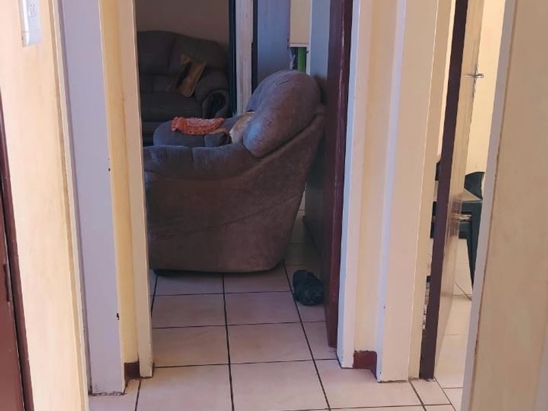 A narrow interior hallway featuring tiled flooring and connecting multiple rooms within the home.