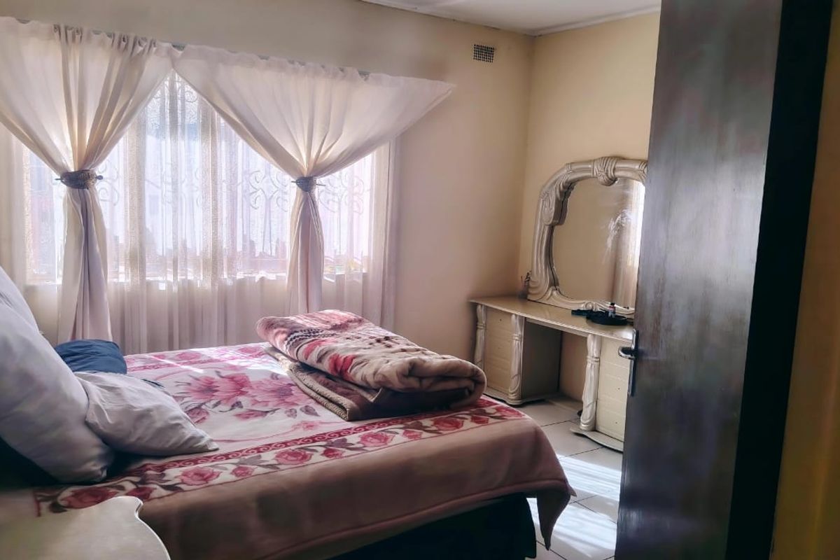 A standard bedroom featuring a window with curtain rails and a ventilation grille, providing a functional space for rest.