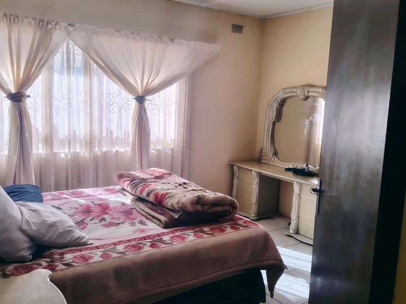 A standard bedroom featuring a window with curtain rails and a ventilation grille, providing a functional space for rest.