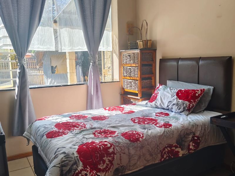 A functional bedroom featuring tiled flooring and a large window that allows for natural light.