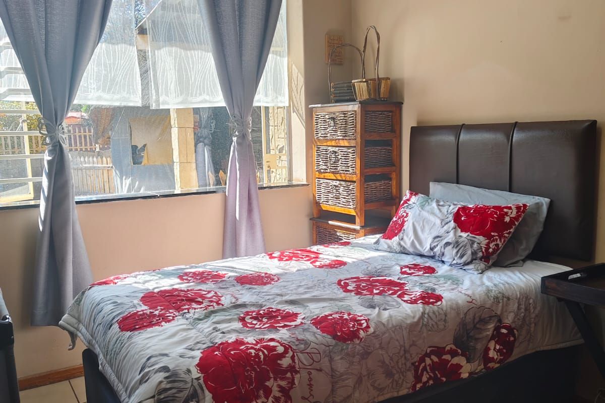 A functional bedroom featuring tiled flooring and a large window that allows for natural light.