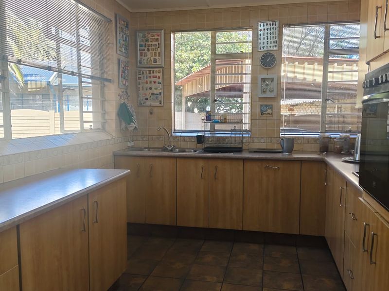 A functional kitchen featuring wood-look cabinetry, laminate countertops, tiled splashbacks, and built-in oven, offering a practical layout with ample natural light.