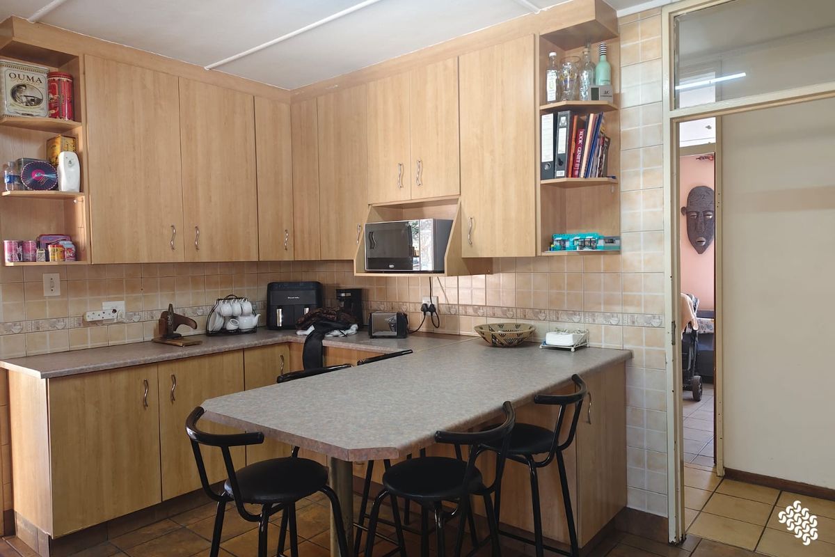 A functional kitchen featuring light wood-look cabinetry, laminate countertops with an integrated breakfast bar, and tiled finishes throughout.
