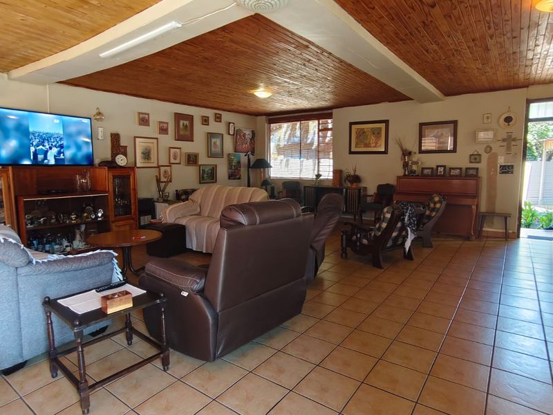 Spacious living area featuring a warm timber-clad ceiling, ceramic tiled flooring, and an exposed structural beam, offering a comfortable and traditional living space.