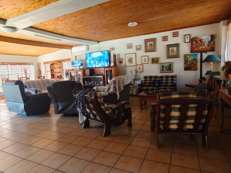 Spacious living area featuring a warm timber-clad ceiling, neutral ceramic floor tiles, and a wall-mounted air conditioning unit.