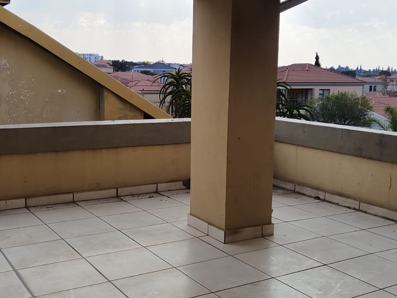 Spacious open-air balcony featuring tiled flooring and a structural support column, offering an elevated view of the surrounding residential neighborhood.