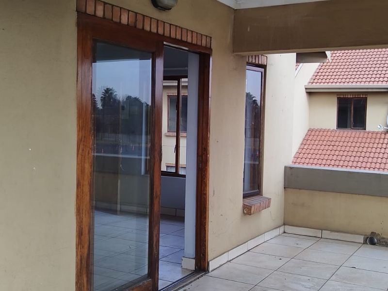 A spacious covered balcony featuring tiled flooring and sliding glass door access, offering a functional outdoor area for the penthouse.