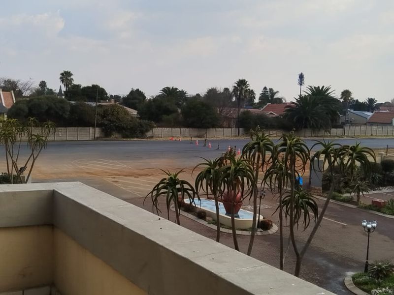 Elevated view overlooking the complex grounds, featuring paved driveway areas, landscaped gardens, and a water feature.
