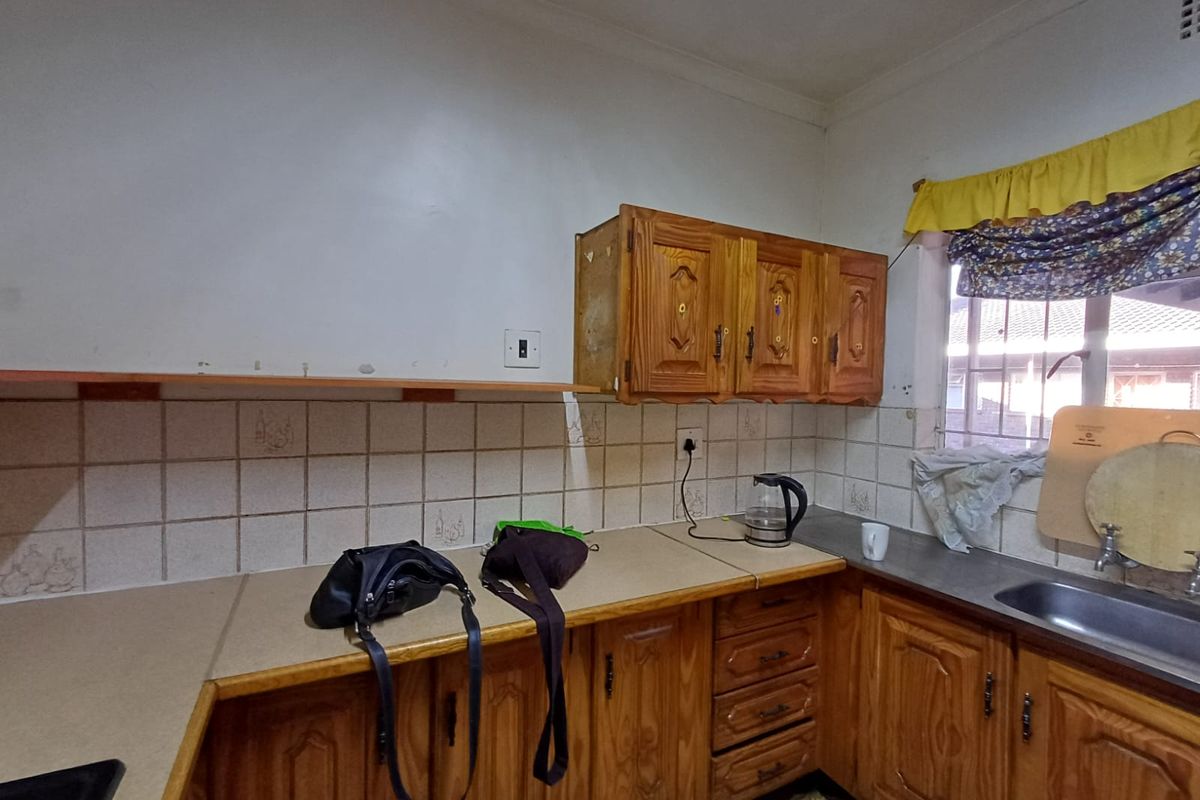 A dated kitchen featuring wooden cabinetry, laminate countertops, and a tiled backsplash, offering significant potential for a modern renovation.