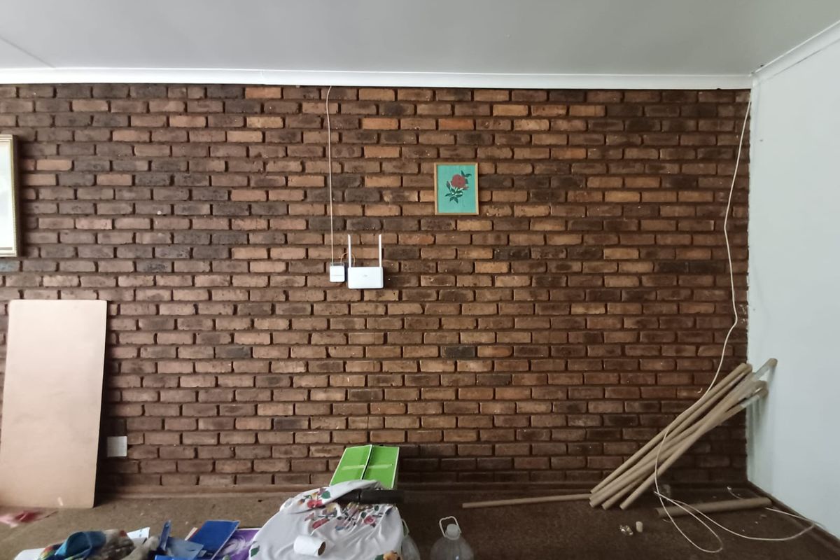 A living room space featuring a prominent exposed brick feature wall and ceiling coving, offering a rustic aesthetic ready for interior design updates.