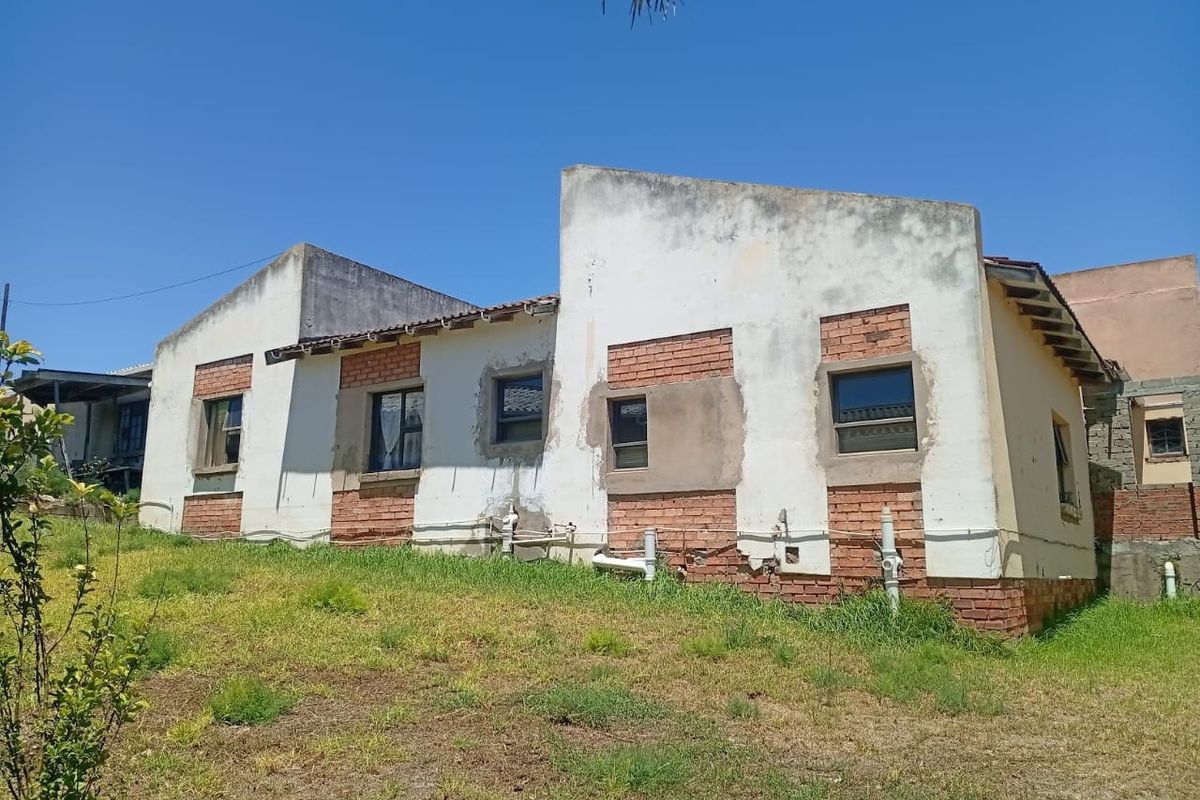 Rear view of a house showing exposed brickwork and plastered walls in need of maintenance and exterior finishing.