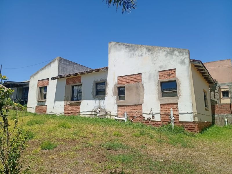 Rear view of a house showing exposed brickwork and plastered walls in need of maintenance and exterior finishing.