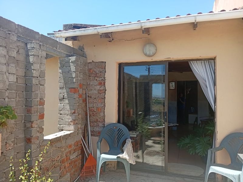 Outdoor patio area featuring a sliding glass door entrance and exposed brick wall structure, requiring maintenance and finishing to improve the exterior aesthetic.