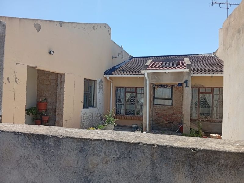 Front view of a single-story house showing significant exterior wear, including peeling paint and exposed brickwork on the facade.