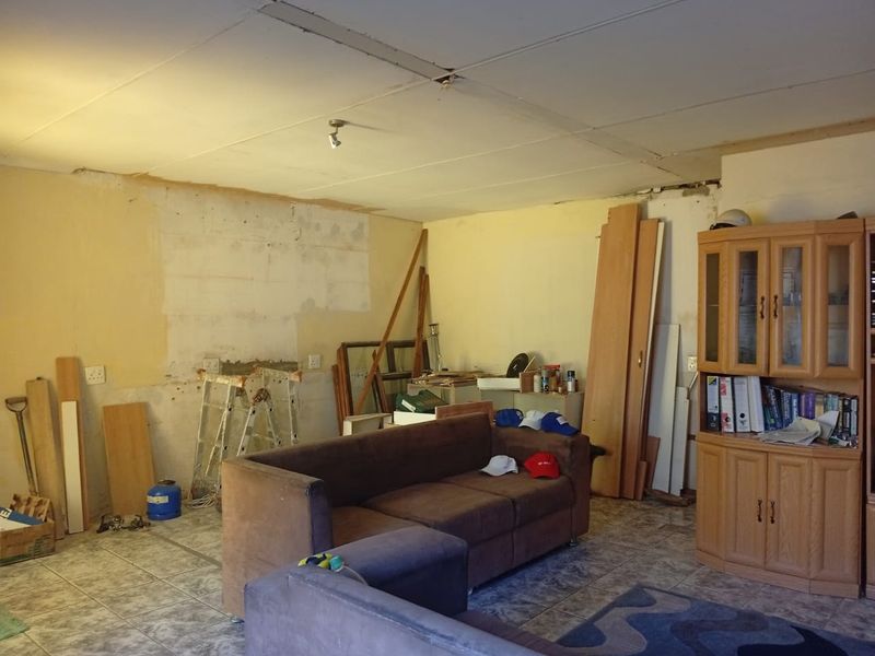 A living area in need of renovation, featuring tiled floors and unfinished wall and ceiling surfaces.