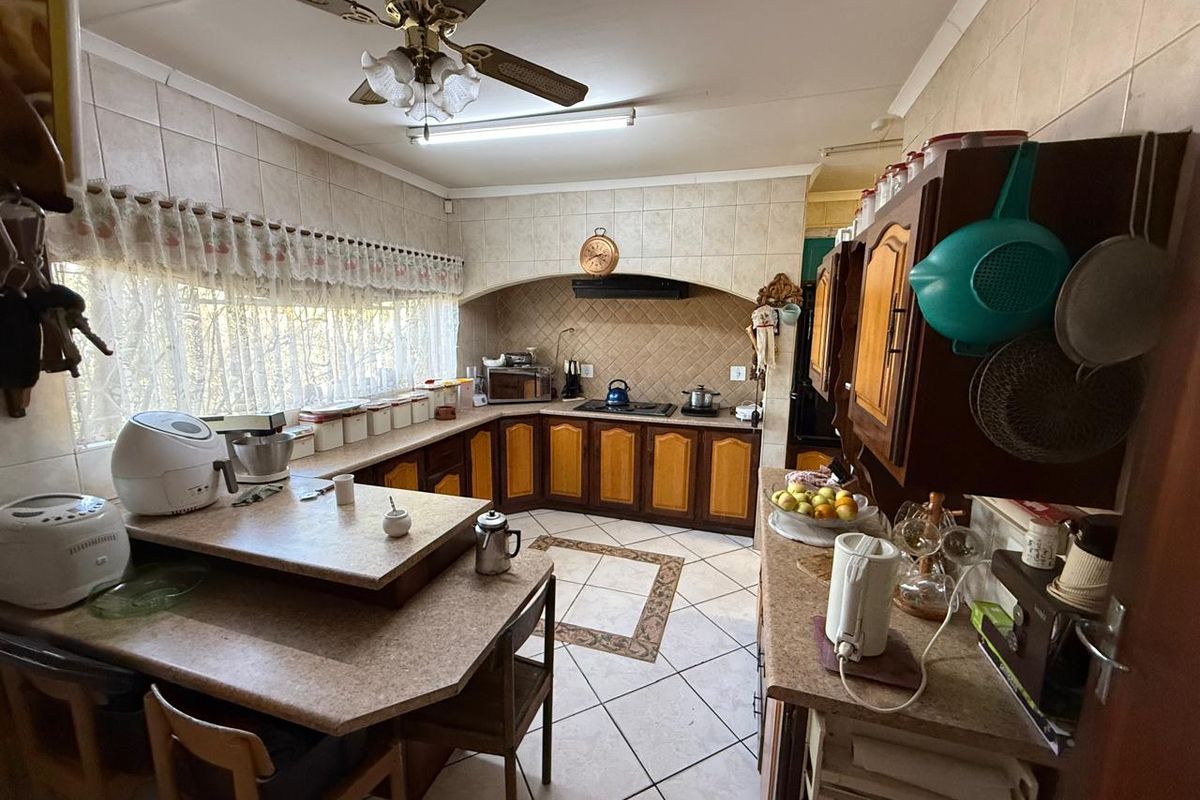 A functional kitchen featuring tiled flooring, extensive built-in cabinetry, a tiled backsplash, and a ceiling fan, offering a traditional layout with ample counter space.
