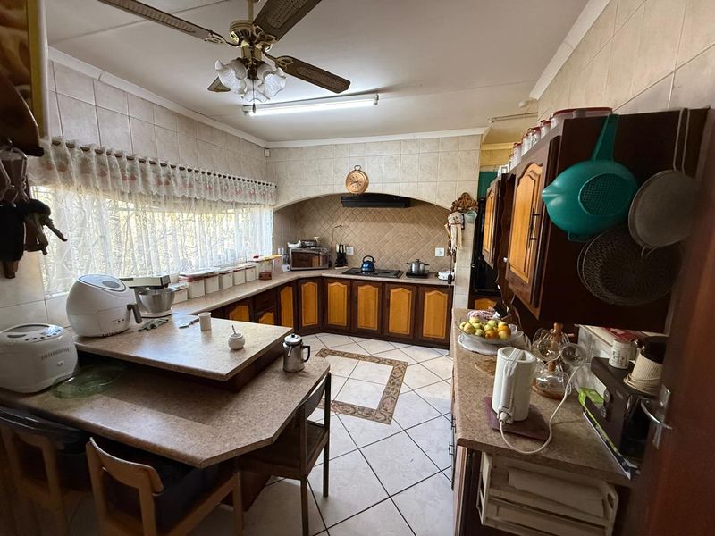 A functional kitchen featuring tiled flooring, extensive built-in cabinetry, a tiled backsplash, and a ceiling fan, offering a traditional layout with ample counter space.