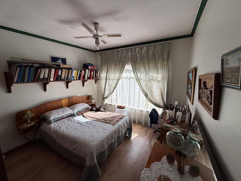 A bedroom featuring laminate flooring, a ceiling fan, and a built-in wooden headboard with integrated shelving.