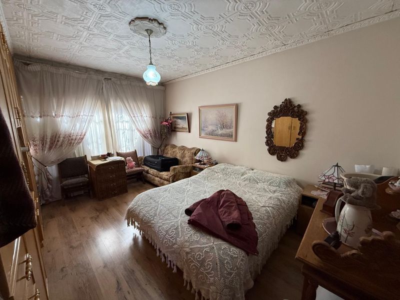 A bedroom featuring laminate flooring and decorative ceiling tiles with a central ceiling rose and built-in wardrobe storage.