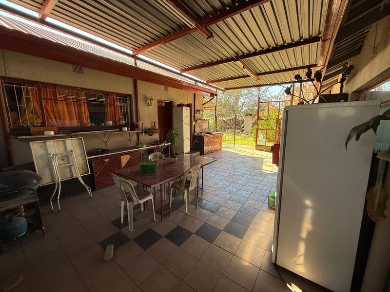 A covered outdoor patio area featuring tiled flooring and a corrugated metal roof, providing a functional space for outdoor living and entertaining.