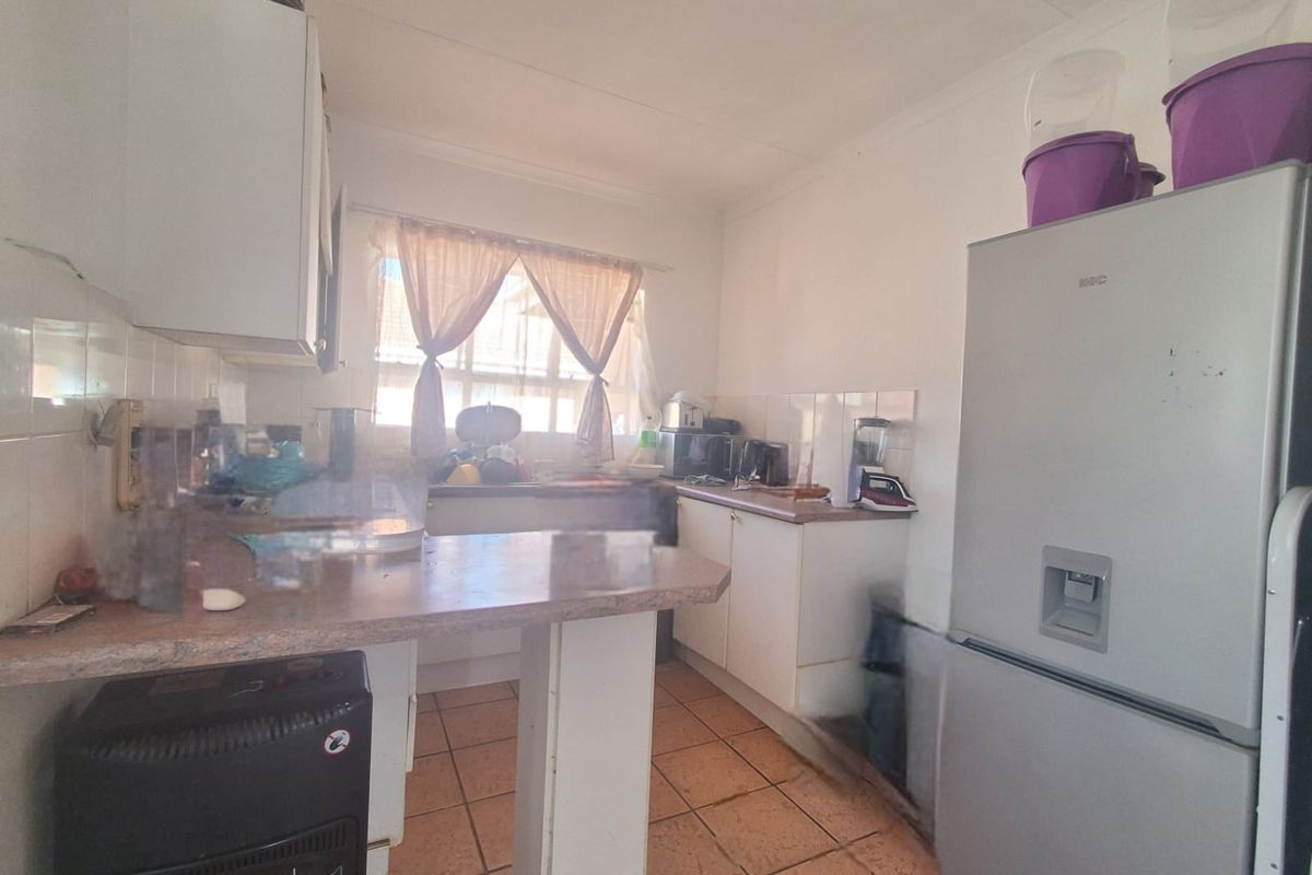 A functional kitchen featuring tiled flooring, laminate countertops, and built-in cabinetry, offering a practical layout with potential for modernization.