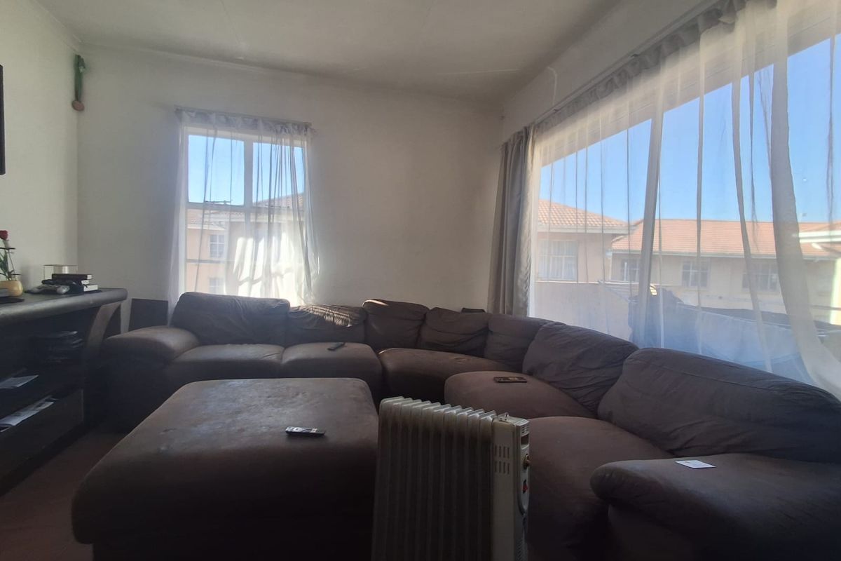 A spacious living room featuring large windows that provide ample natural light and views of the surrounding residential area.