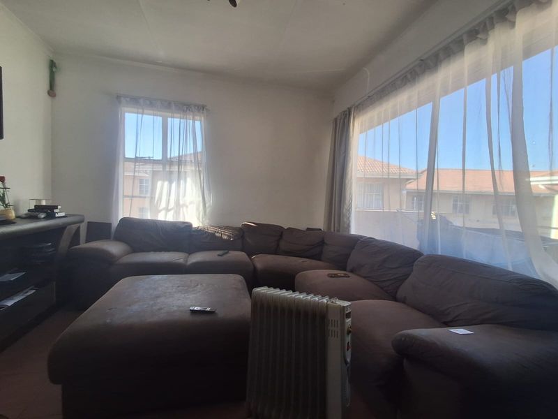 A spacious living room featuring large windows that provide ample natural light and views of the surrounding residential area.