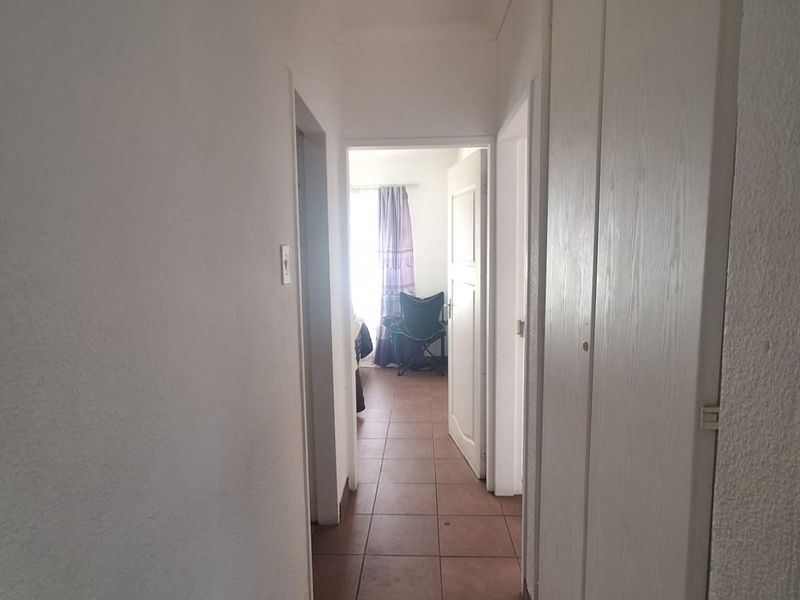 A functional hallway featuring tiled flooring and built-in storage cupboards, providing access to adjacent rooms.