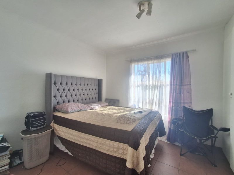 A bedroom featuring tiled flooring and a window with curtain rails, providing a functional space with natural light.