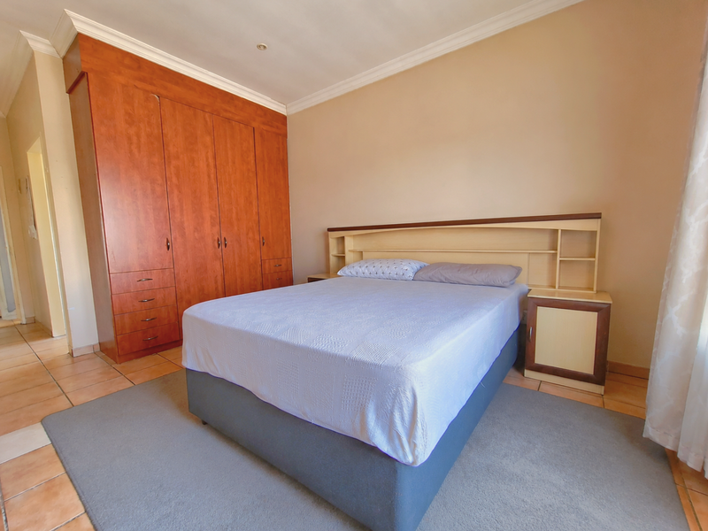A bedroom featuring built-in wooden cabinetry, a matching integrated headboard with shelving, and tiled flooring.
