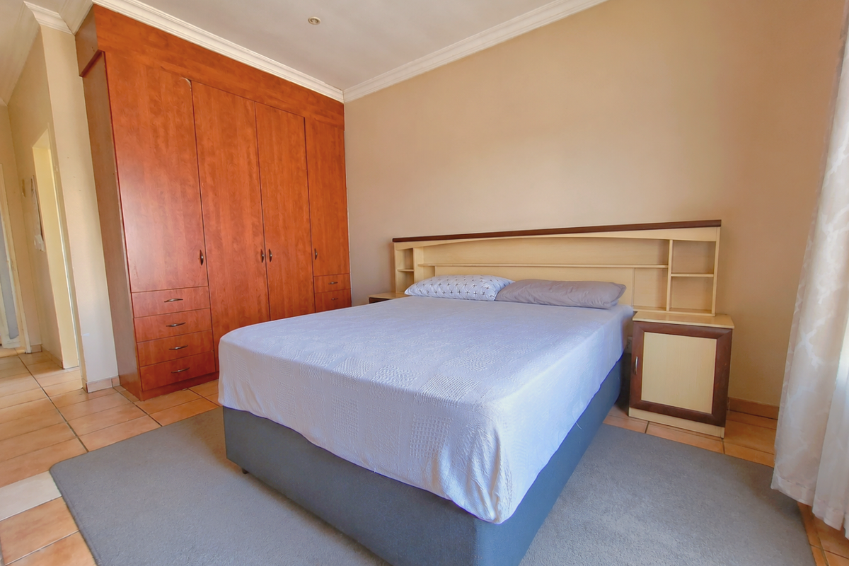 A bedroom featuring built-in wooden cabinetry, a matching integrated headboard with shelving, and tiled flooring.