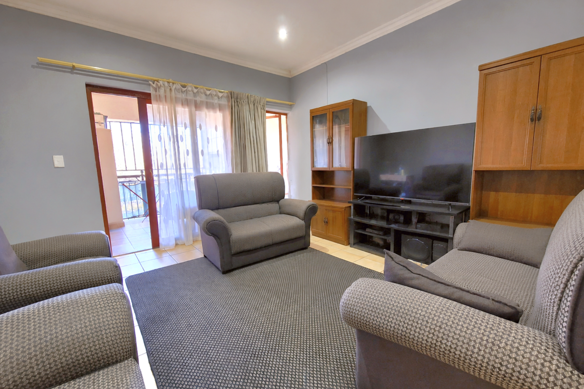 A comfortable living room featuring tiled flooring and a sliding glass door providing access to an outdoor balcony area.