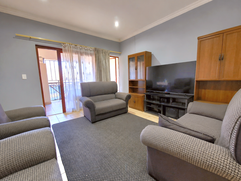 A comfortable living room featuring tiled flooring and a sliding glass door providing access to an outdoor balcony area.