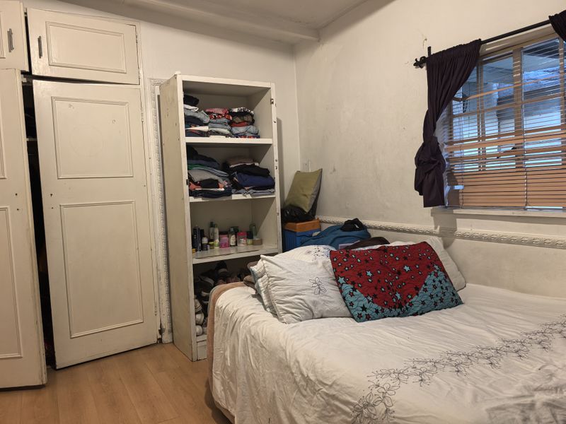 A bedroom featuring laminate flooring, built-in wardrobe storage, and decorative wall molding, requiring cosmetic updates to improve the overall finish.