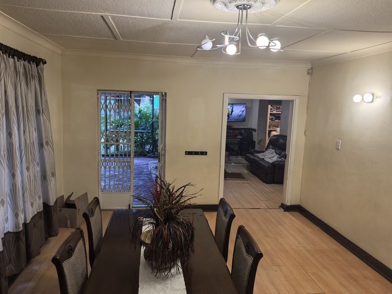 Dining room featuring laminate flooring, coved ceilings with a decorative rose, and direct access to an outdoor area through a security gate.