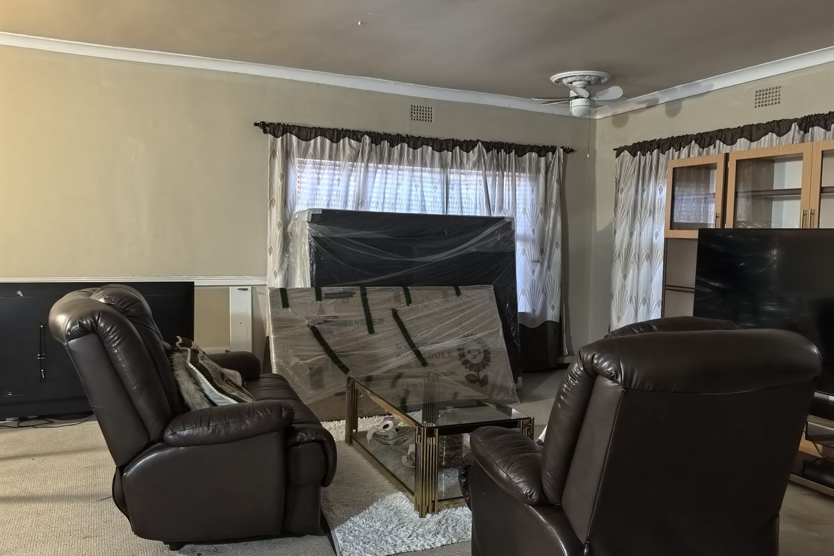 A living room featuring a ceiling fan, built-in cabinetry, and carpet flooring. The space shows signs of wear and requires cosmetic updates.