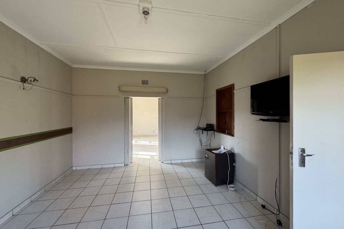 An empty living room featuring tiled flooring and neutral wall finishes, providing a blank canvas for potential interior design and renovation.